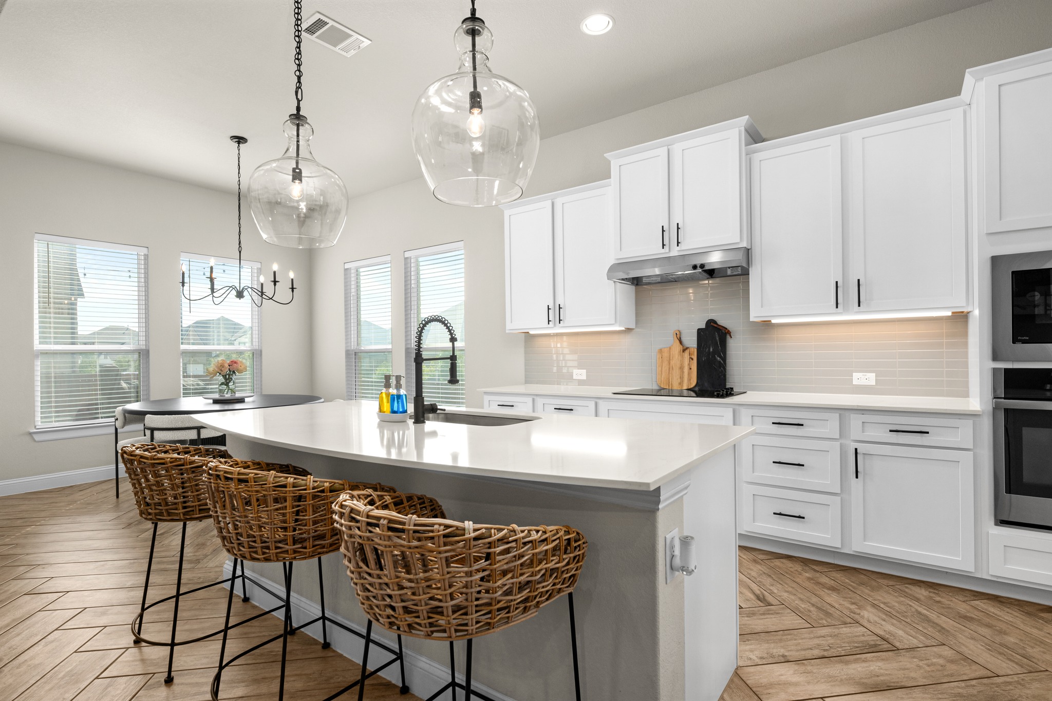 2100 Highland Ridge Road Georgetown, TX 78628 - Photo 12 of 30 A well-lit kitchen with sleek white cabinetry, a spacious island, and wood plank flooring.