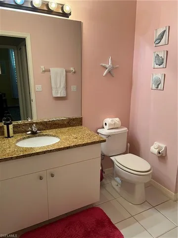 a bathroom with a granite countertop toilet a sink and a mirror