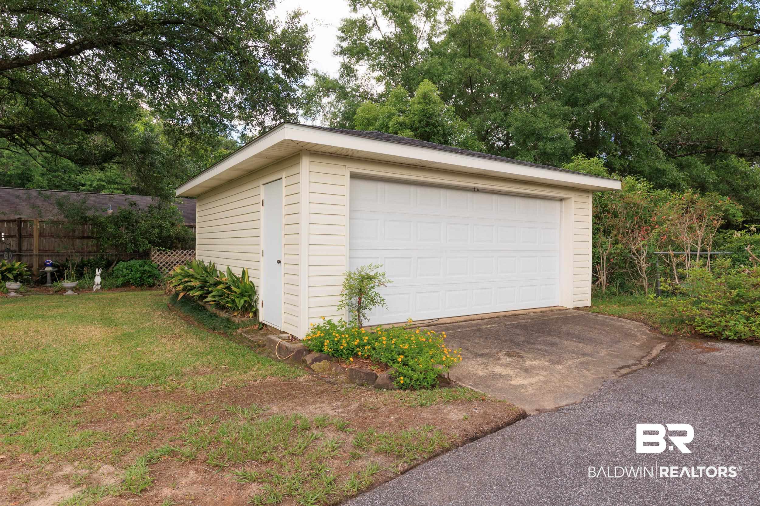 1367 Spring Valley Court Mobile, AL 36693 - Photo 26 of 29 Detached garage with panel-style door and side entry, featuring light-toned siding and a partial asphalt driveway