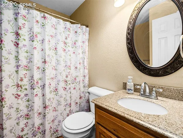 a bathroom with a granite countertop toilet a sink and a mirror