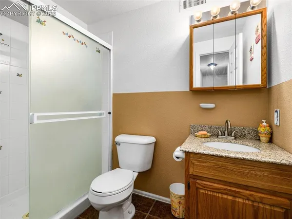 a bathroom with a granite countertop toilet sink and mirror