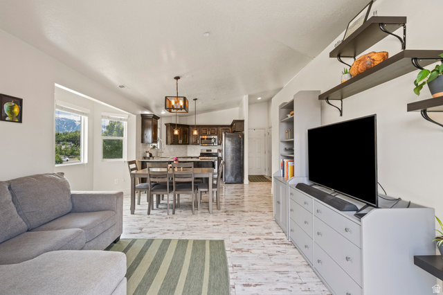 8248 South Resaca Drive, Unit J10 Sandy, UT 84070 - Photo 7 of 40 Open-concept living space featuring wood-finish flooring, a kitchen with dark wood cabinetry and stainless steel appliances, and built-in shelving