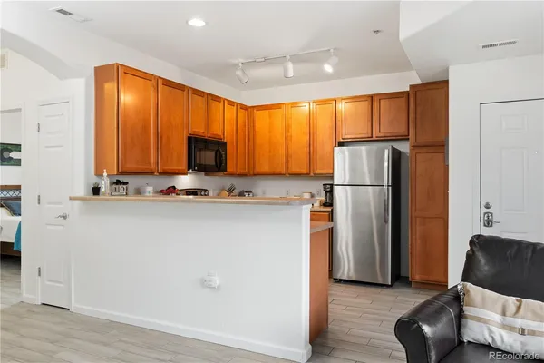 a view of kitchen with stainless steel appliances granite countertop a refrigerator and a couch
