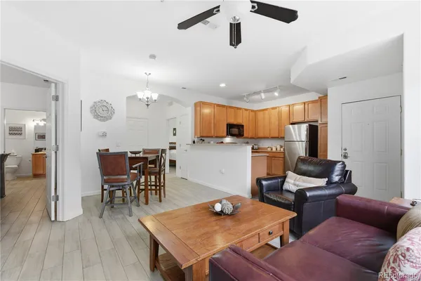 a living room with furniture kitchen view and a wooden floor
