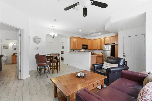 a living room with furniture kitchen view and a wooden floor