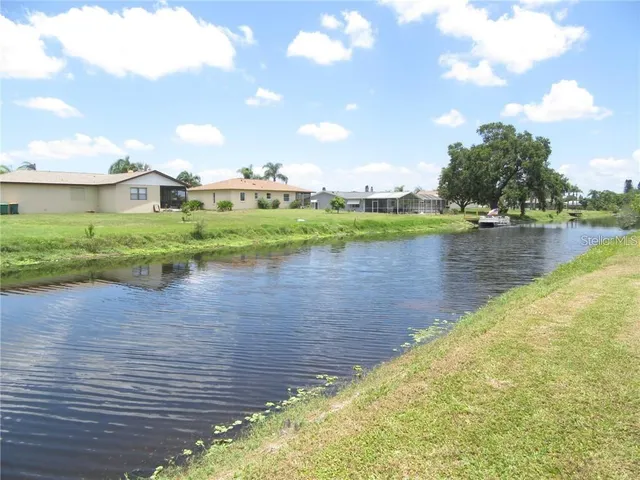 a view of a lake with a yard and large trees