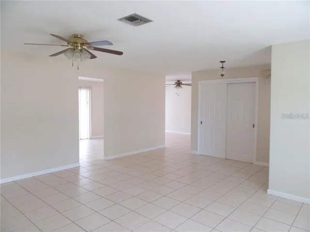 a view of an empty room and chandelier fan