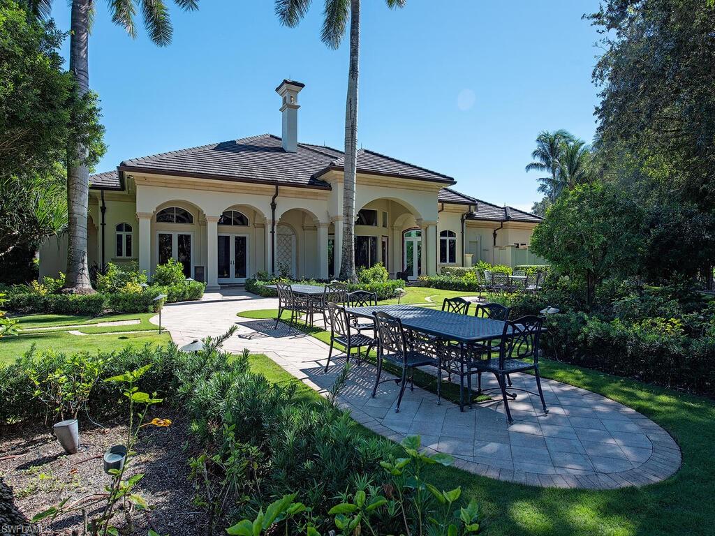 6955 Verde Way Naples, FL 34108 - Photo 42 of 42 a front view of a house with garden and patio
