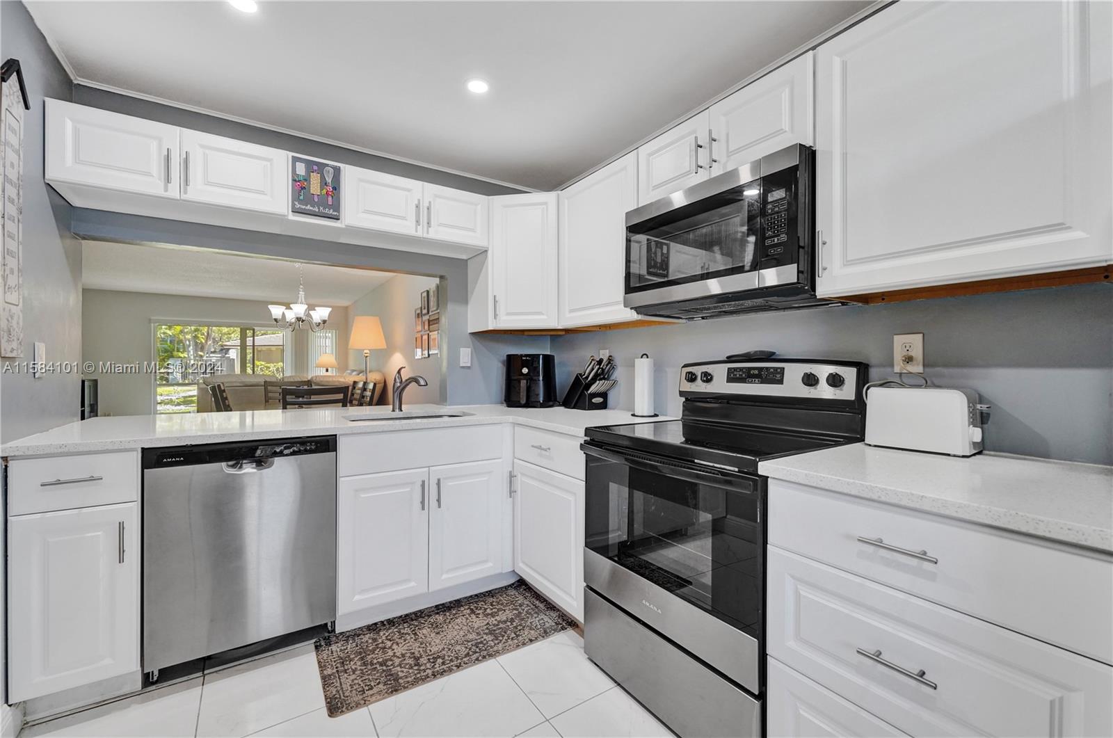 a kitchen with stainless steel appliances granite countertop white cabinets a stove a microwave and a sink