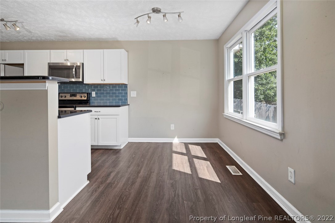 6573 Applewhite Road Fayetteville, NC 28304 - Photo 12 of 35 a kitchen with wooden floors and white cabinets