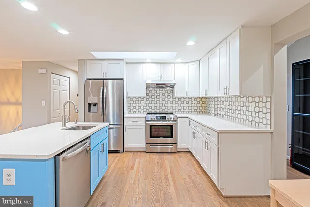 a kitchen with stainless steel appliances kitchen island granite countertop a sink stove and refrigerator