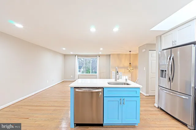 a kitchen with granite countertop a refrigerator sink and white cabinets