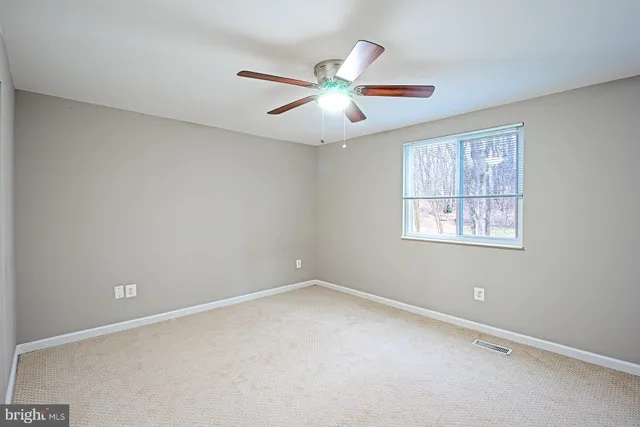 an empty room with a window and a fan