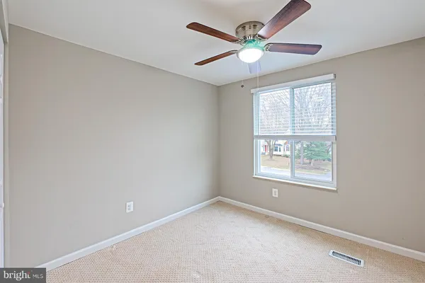 an empty room with a window and a fan