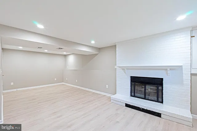 an empty room with wooden floor and fireplace