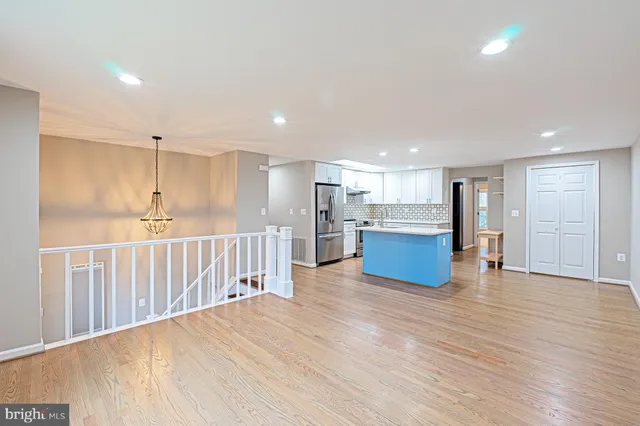 a view of a kitchen with kitchen island a sink wooden floor and a refrigerator
