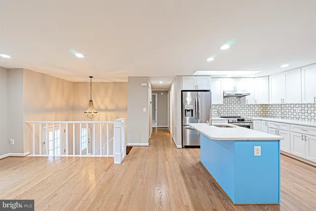 a kitchen with stainless steel appliances granite countertop a refrigerator oven a sink dishwasher and white cabinets with wooden floor