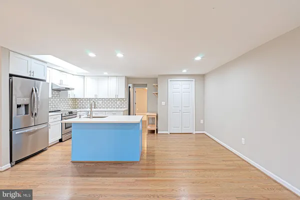 a large kitchen with a center island wooden floor and stainless steel appliances