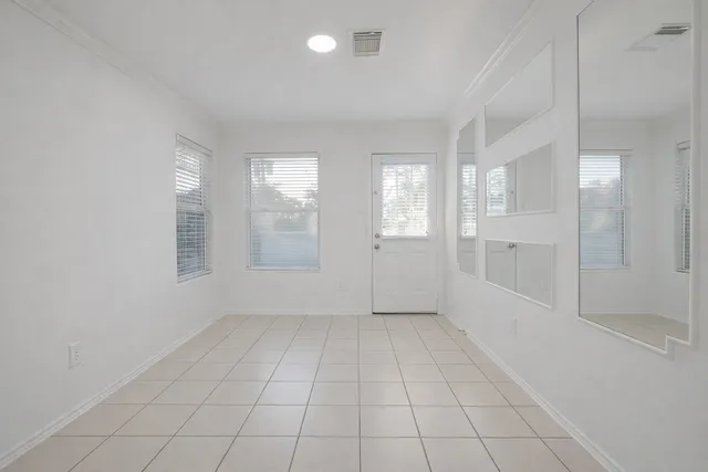 a view of an empty room with window and chandelier fan