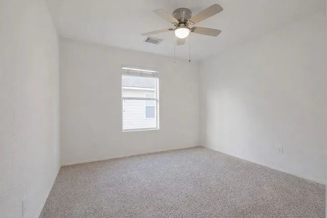 an empty room with a window and a fan