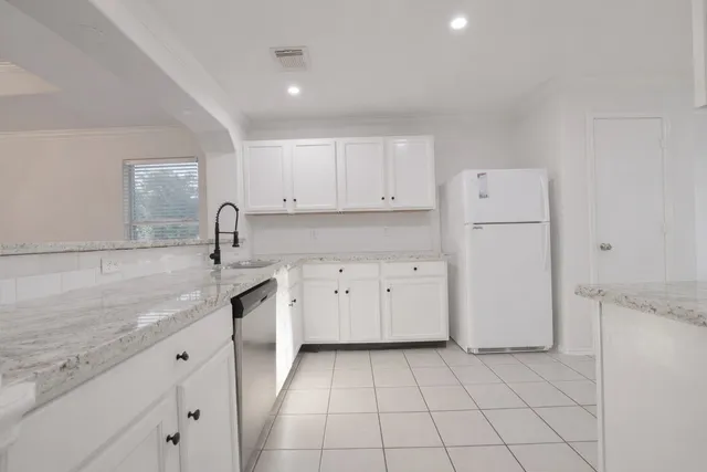 a kitchen with white cabinets and refrigerator