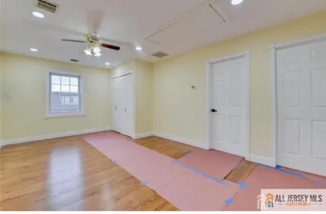 a view of an empty room with window and wooden floor