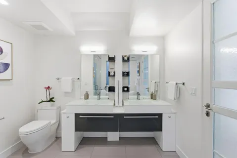 a bathroom with a double vanity sink toilet and shower