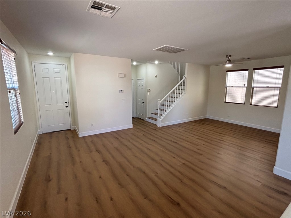 4900 Naff Ridge Drive Las Vegas, NV 89131 - Photo 7 of 21 Natural wood-look flooring extends through this airy living area, featuring a grand staircase and ample windows.