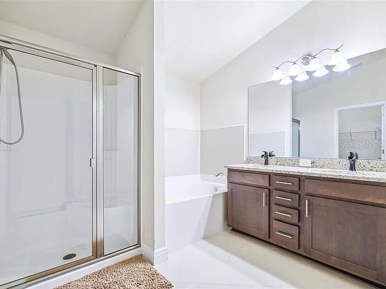 404 Rio Grande Court Poinciana, FL 34759 - Photo 12 of 21 a spacious bathroom with a double vanity sink a large mirror and a bathtub