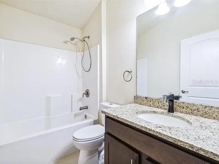 404 Rio Grande Court Poinciana, FL 34759 - Photo 18 of 21 a bathroom with a granite countertop sink a toilet and shower