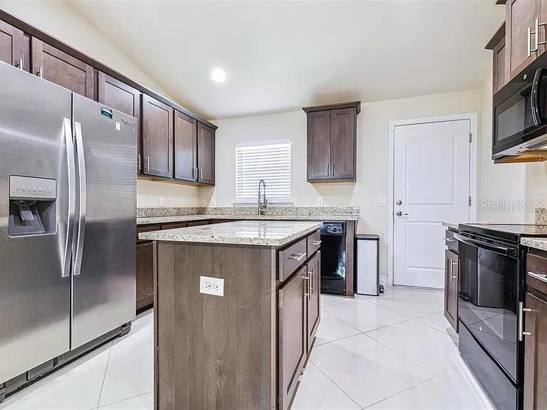 404 Rio Grande Court Poinciana, FL 34759 - Photo 7 of 21 a kitchen with stainless steel appliances granite countertop a refrigerator a sink and white cabinets