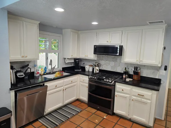a kitchen with white cabinets a sink and appliances