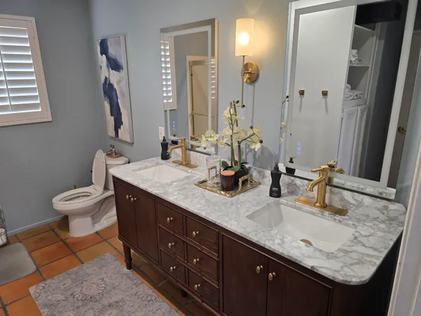 a bathroom with a granite countertop double vanity sink and mirror