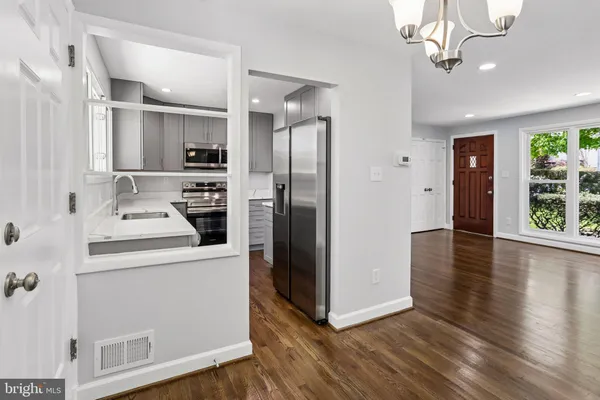 a kitchen view with stainless steel appliances a refrigerator and wooden floor