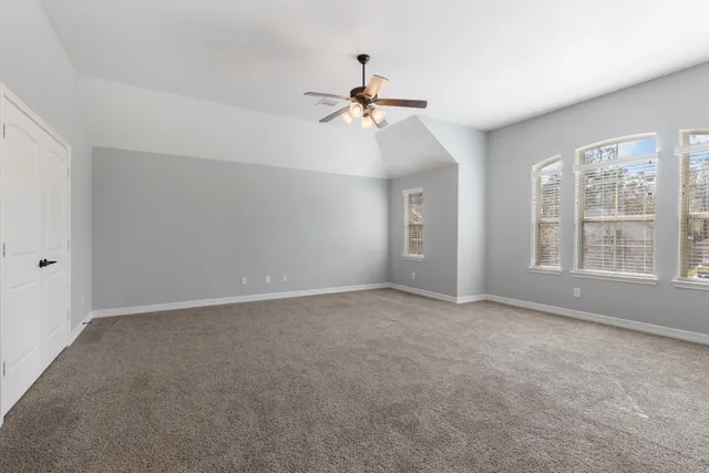 an empty room with windows and fan