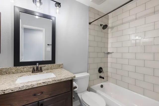 a bathroom with a granite countertop sink a toilet and shower