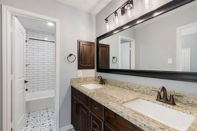 a bathroom with a granite countertop double vanity sink and mirror