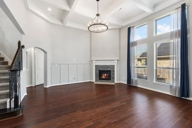 a view of an empty room with wooden floor fireplace and a window