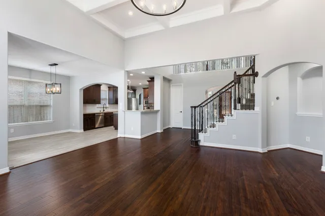 a view of an empty room with wooden floor and a kitchen