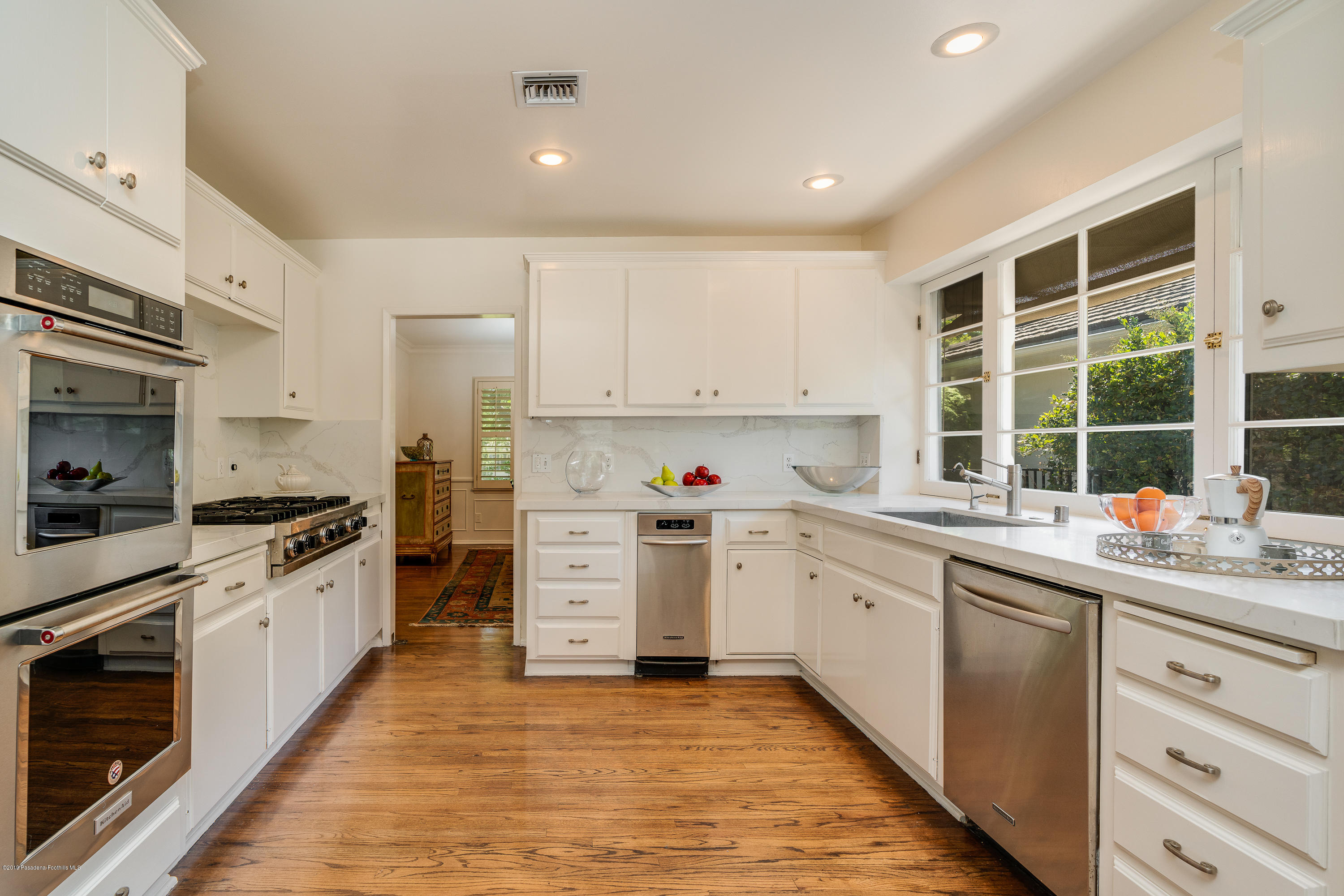 2925 Lorain Road San Marino, CA 91108 - Photo 4 of 18 a kitchen with stainless steel appliances granite countertop a stove top oven a sink dishwasher and white cabinets with wooden floor