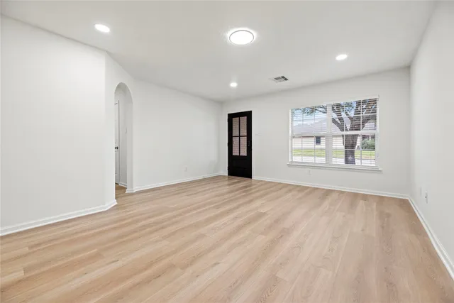 a view of an empty room with a window and wooden floor