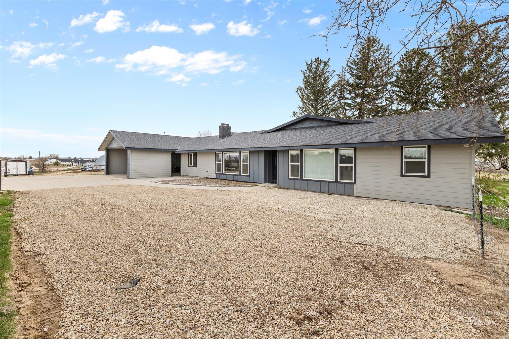 15032 Hollow Road Caldwell, ID 83607 - Photo 17 of 50 Ranch-style home featuring concrete driveway, a garage, roof with shingles, a chimney, and board and batten siding
