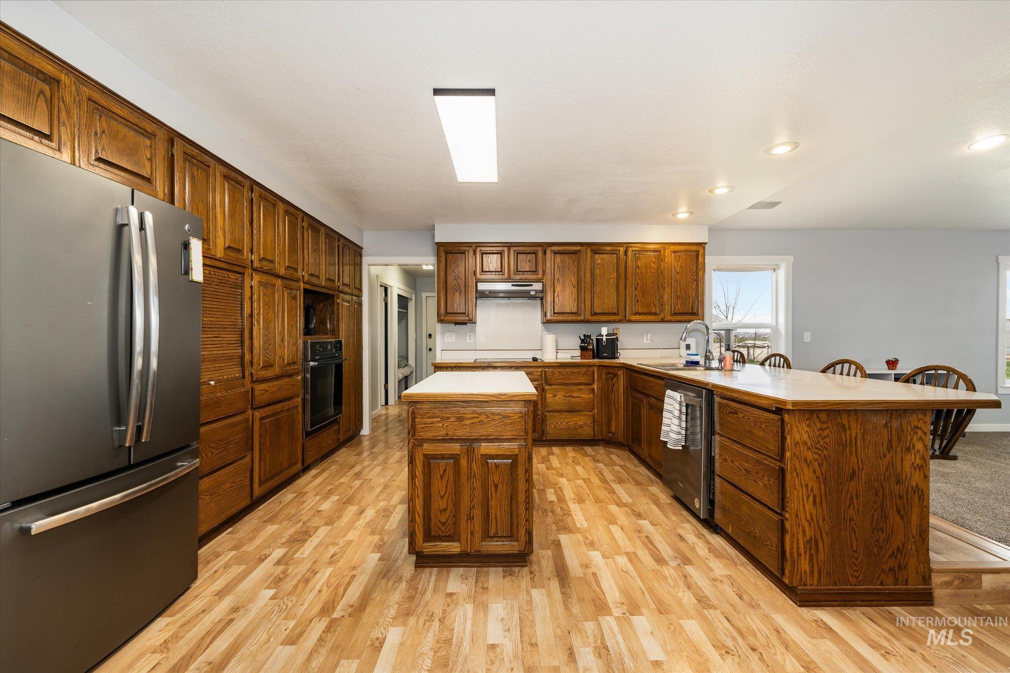 15032 Hollow Road Caldwell, ID 83607 - Photo 21 of 50 Kitchen with stainless steel appliances, a peninsula, wood finish cabinetry, light wood-type flooring, and light countertops