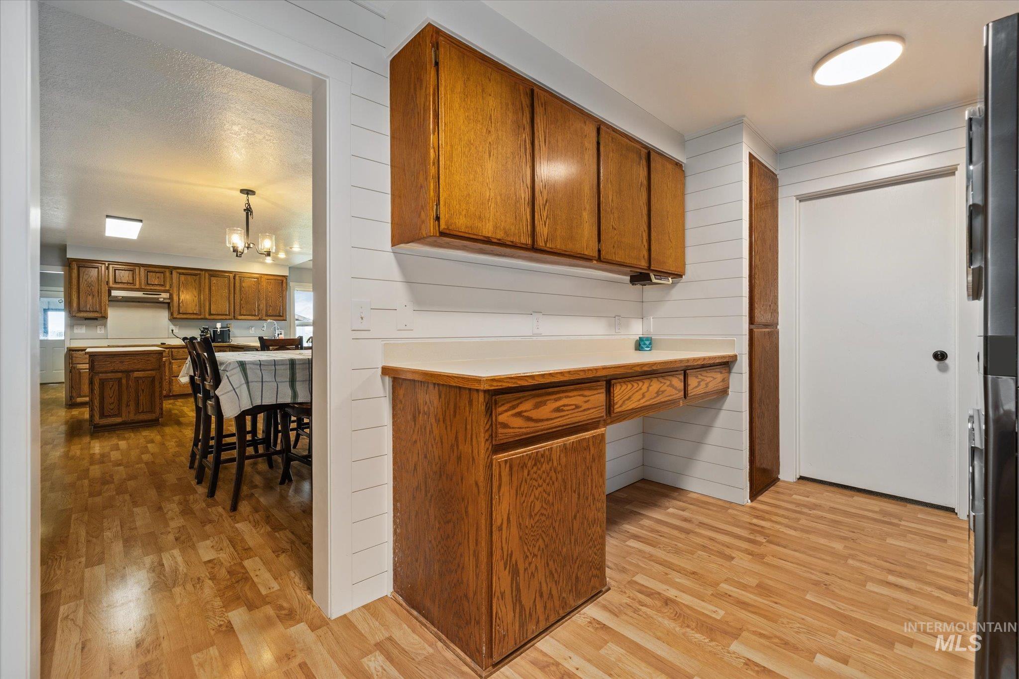 15032 Hollow Road Caldwell, ID 83607 - Photo 25 of 50 Kitchen with wood finish cabinetry, light countertops, suspended lighting, light wood-type flooring, and wood walls