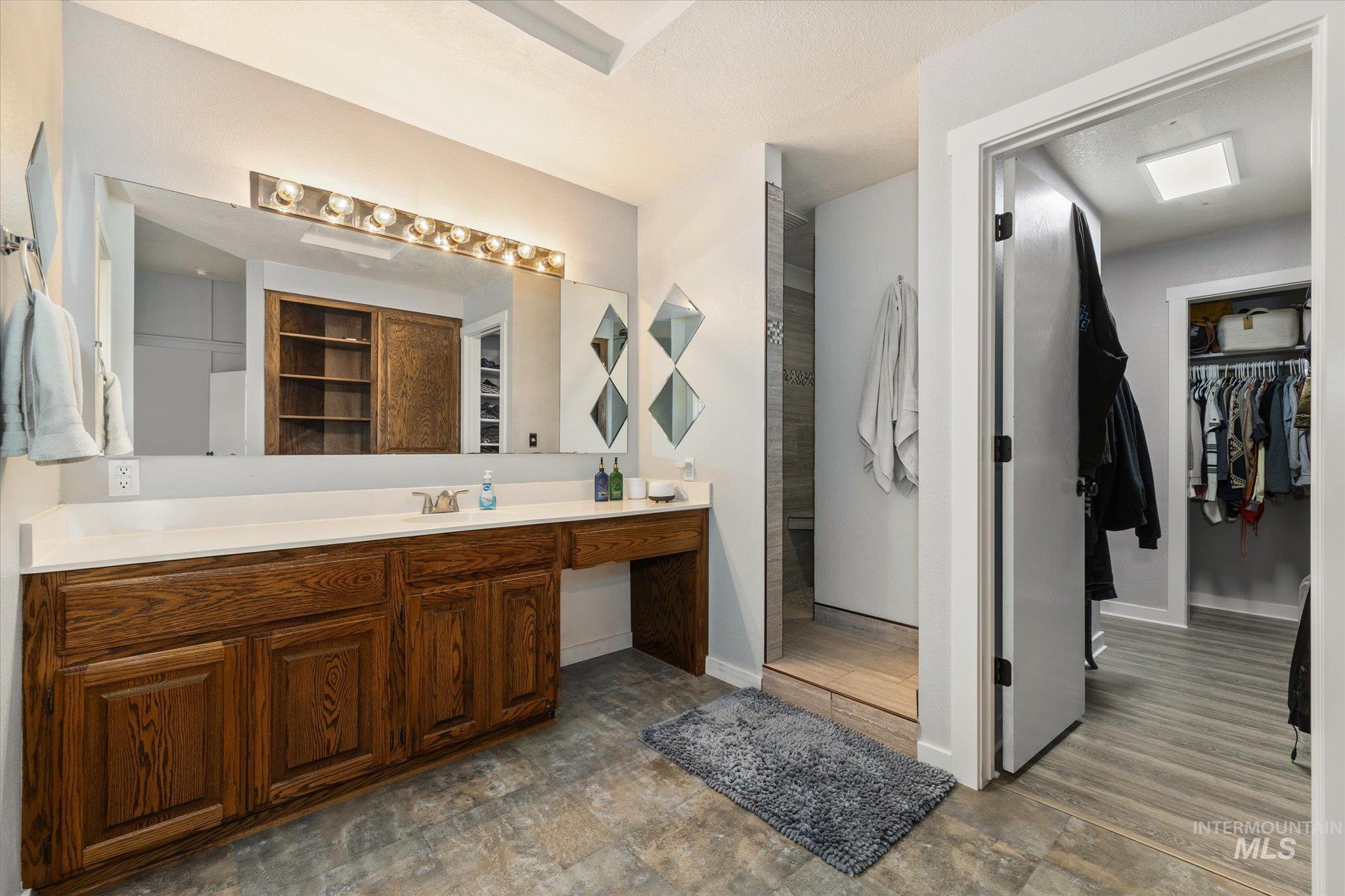 15032 Hollow Road Caldwell, ID 83607 - Photo 27 of 50 Bathroom with a walk in closet, vanity, stone finish floors, and walk in shower