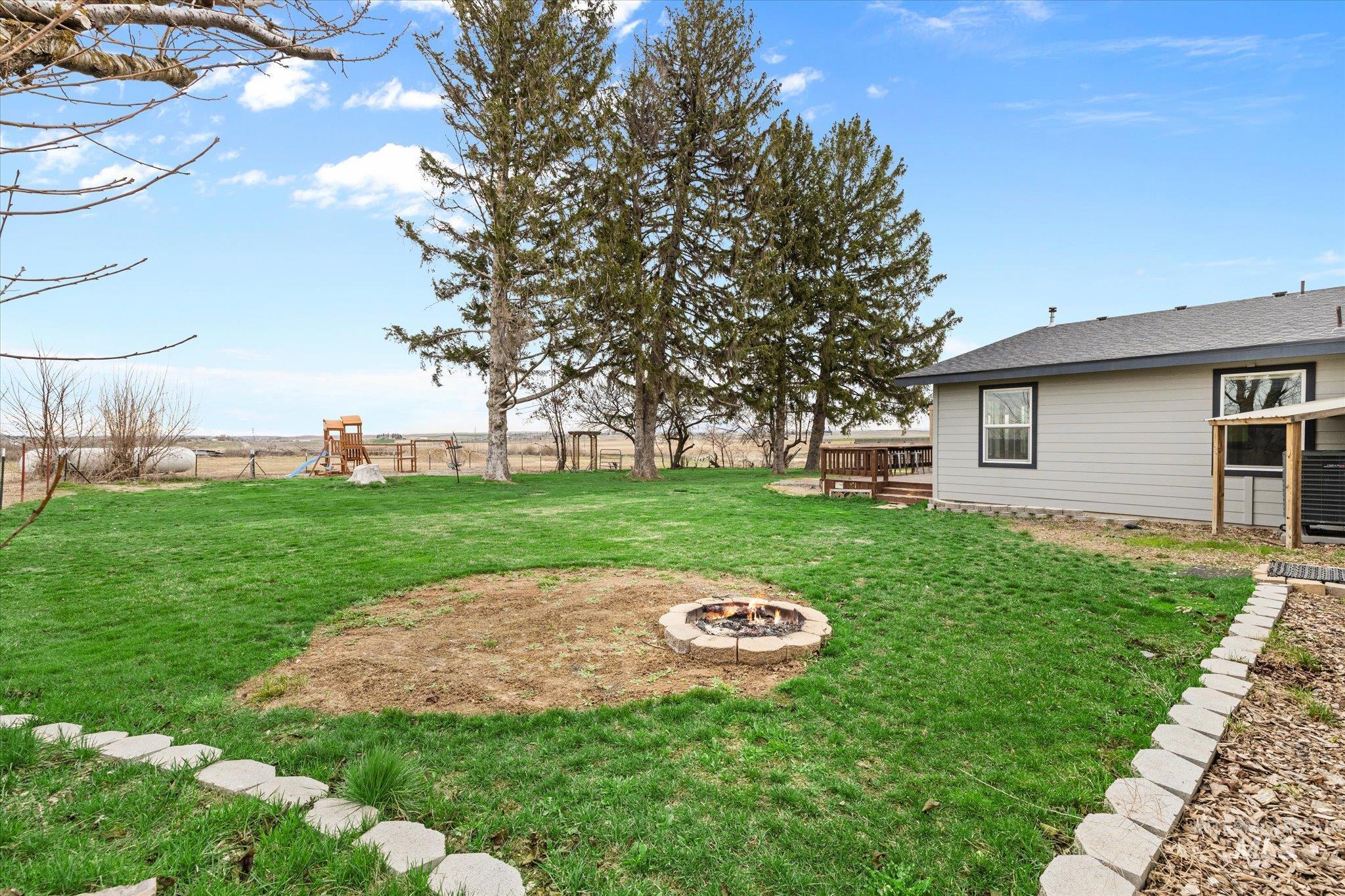 15032 Hollow Road Caldwell, ID 83607 - Photo 39 of 50 Fenced backyard featuring a deck, an outdoor fire pit, and a playground