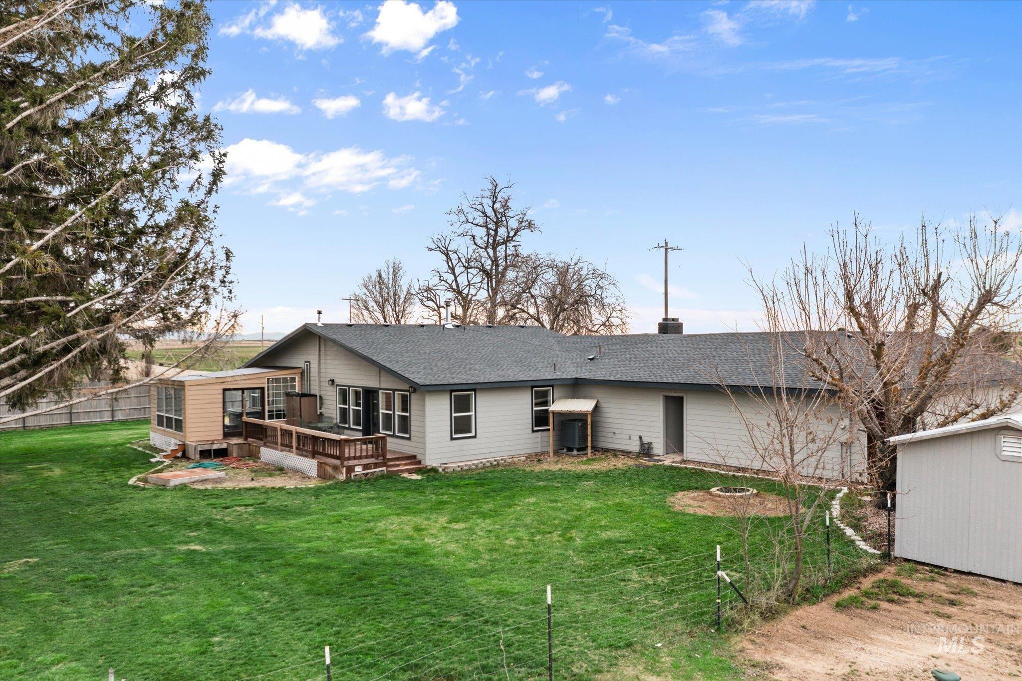 15032 Hollow Road Caldwell, ID 83607 - Photo 4 of 50 Rear view of house with a wooden deck, roof with shingles, a chimney, a fire pit, and a shed