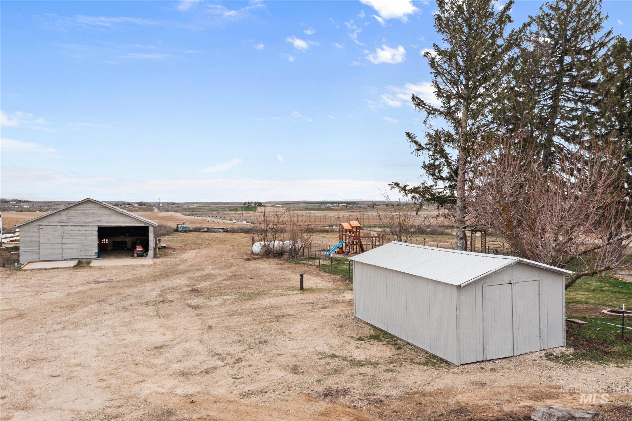15032 Hollow Road Caldwell, ID 83607 - Photo 5 of 50 View of yard featuring a pole building, a rural view, a patio, and a shed