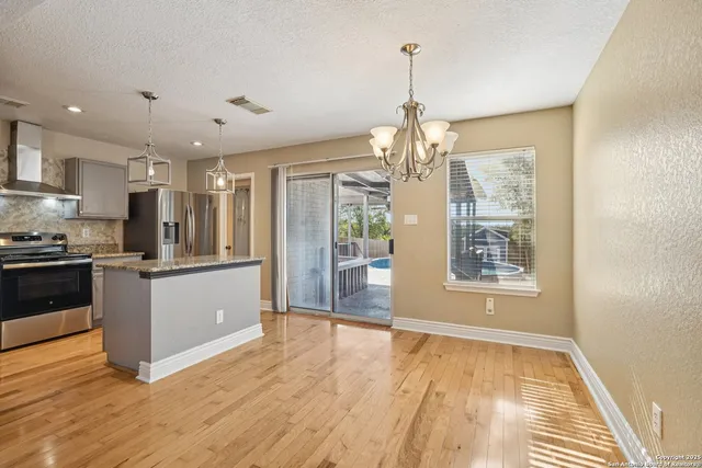 a kitchen with stainless steel appliances granite countertop a refrigerator and a wooden floors