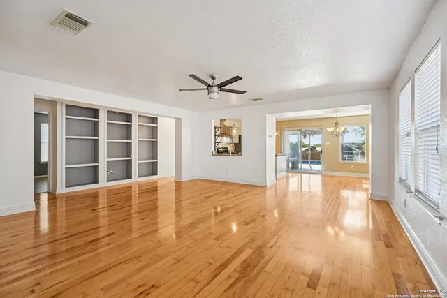 a view of an empty room with wooden floor and a window